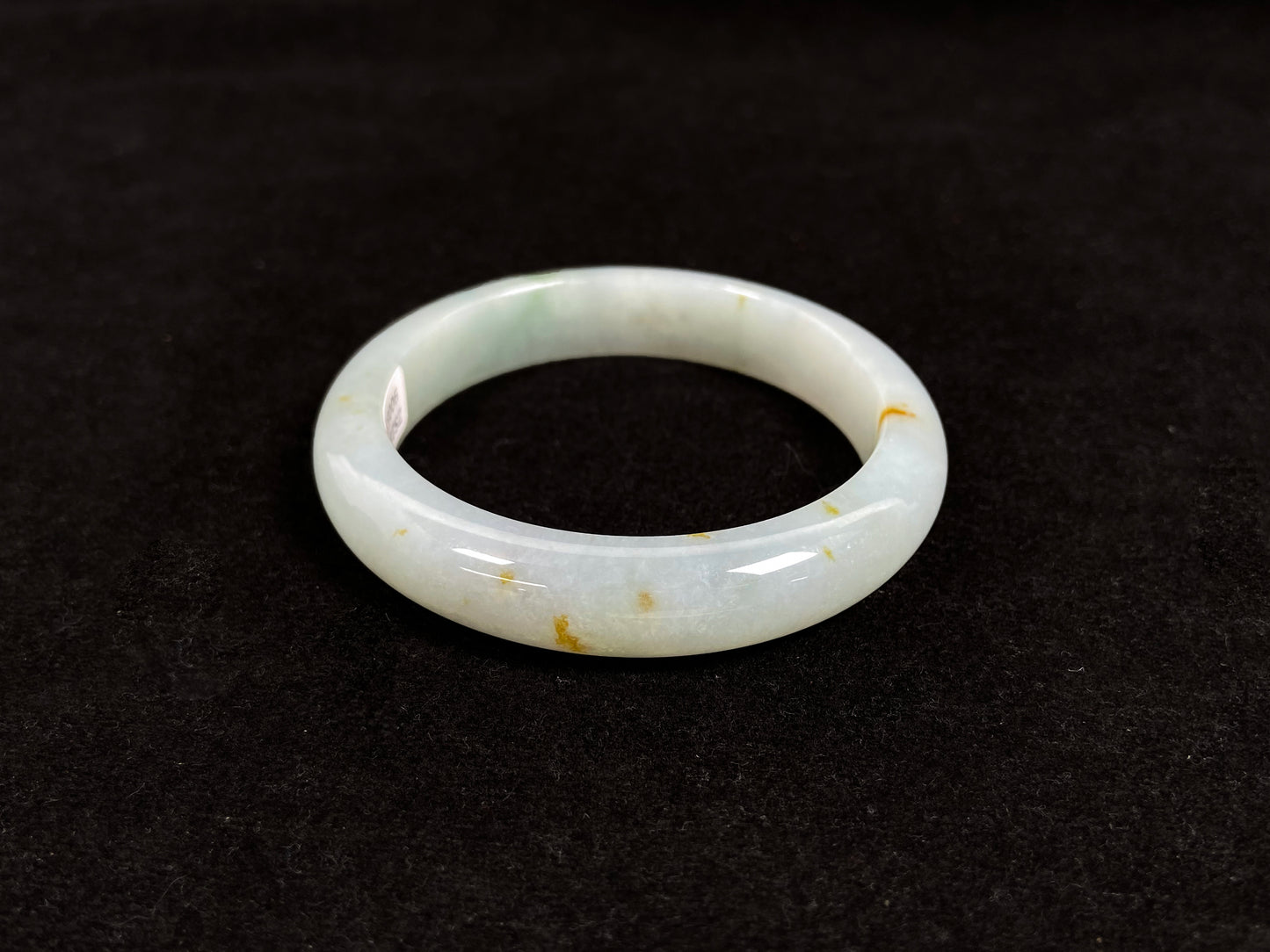 A light green jadeite bangle with gold flecks.