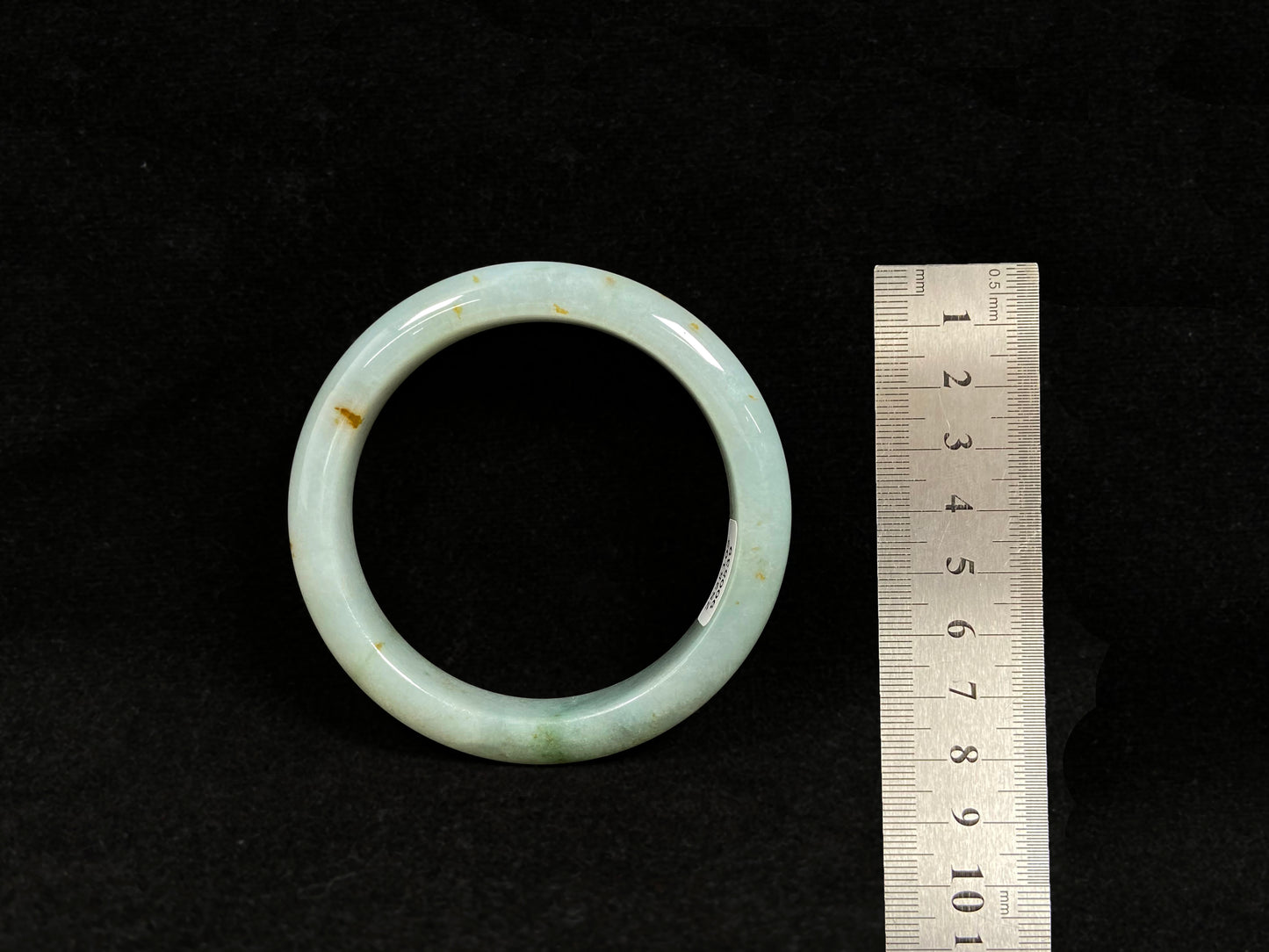 A light green jadeite bangle with gold flecks.