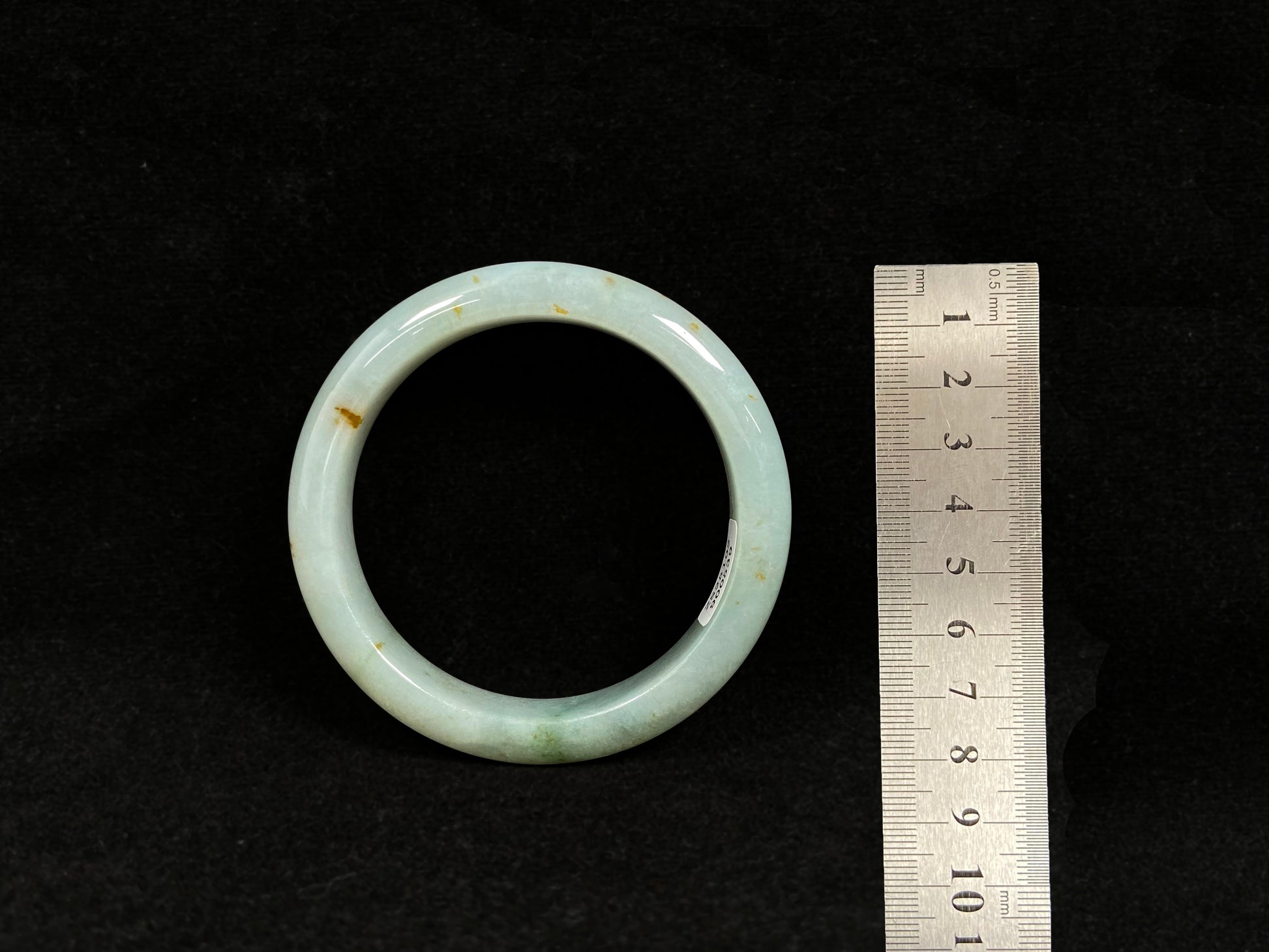 A light green jadeite bangle with gold flecks.