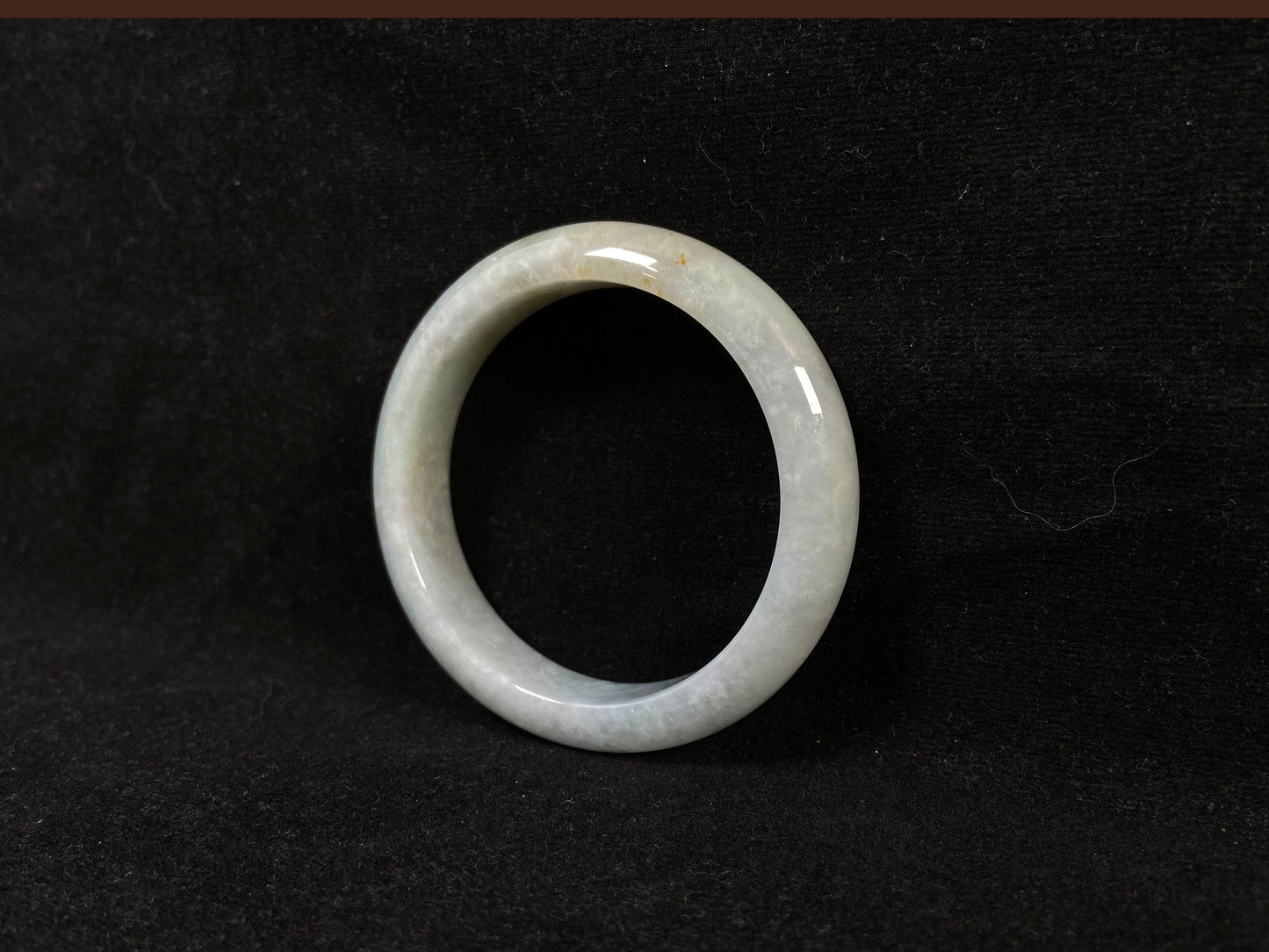 A creamy white jade bangle delicately sprinkled with gold.