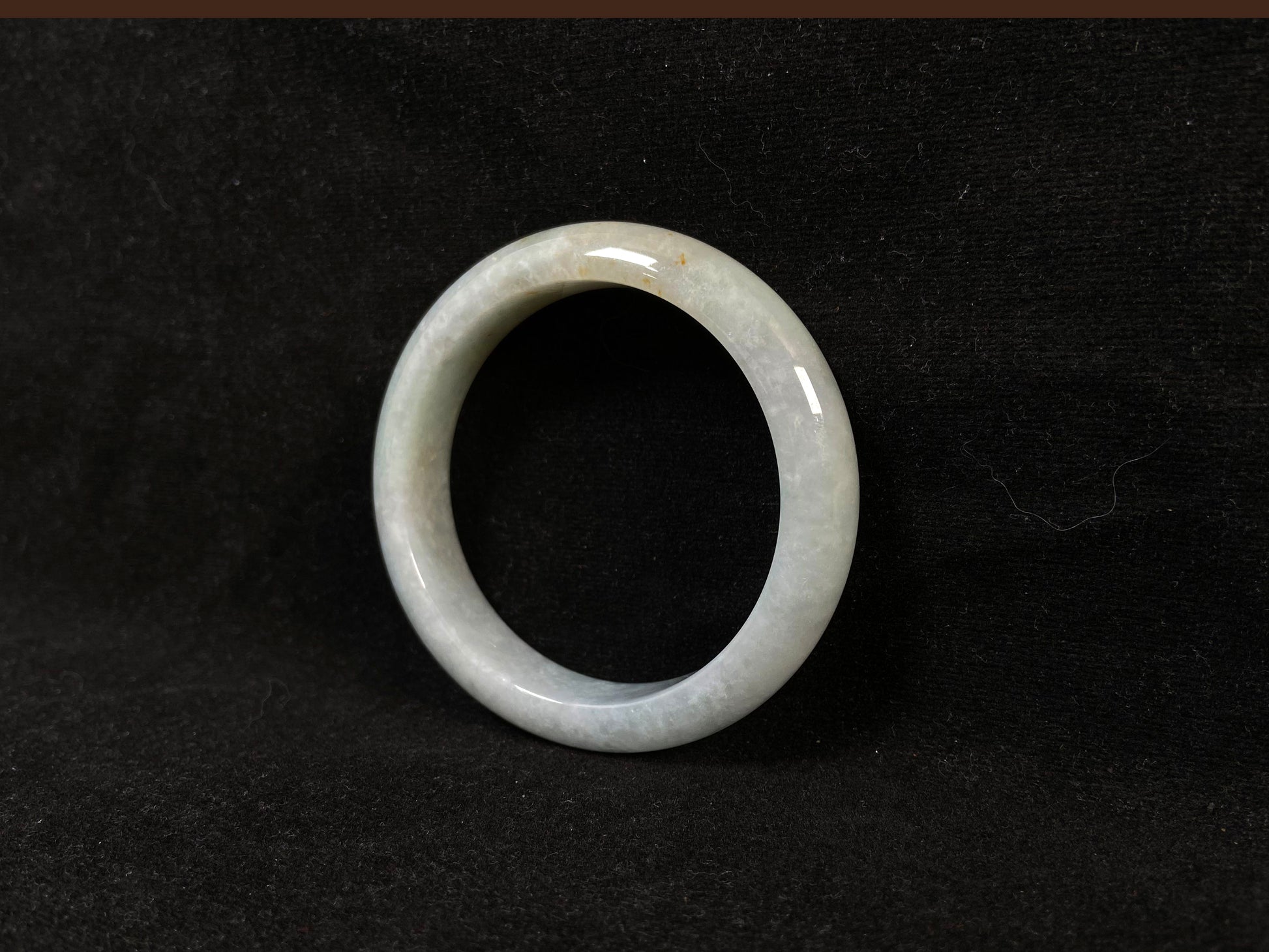 A creamy white jade bangle delicately sprinkled with gold.