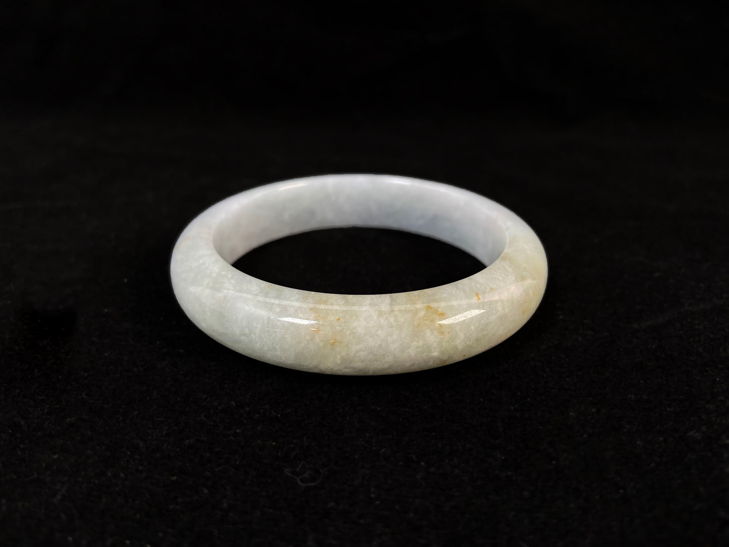 A creamy white jade bangle delicately sprinkled with gold.