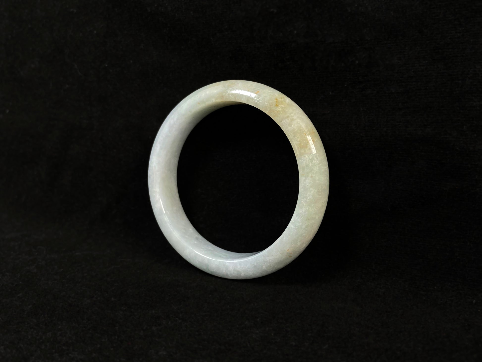 A creamy white jade bangle delicately sprinkled with gold.
