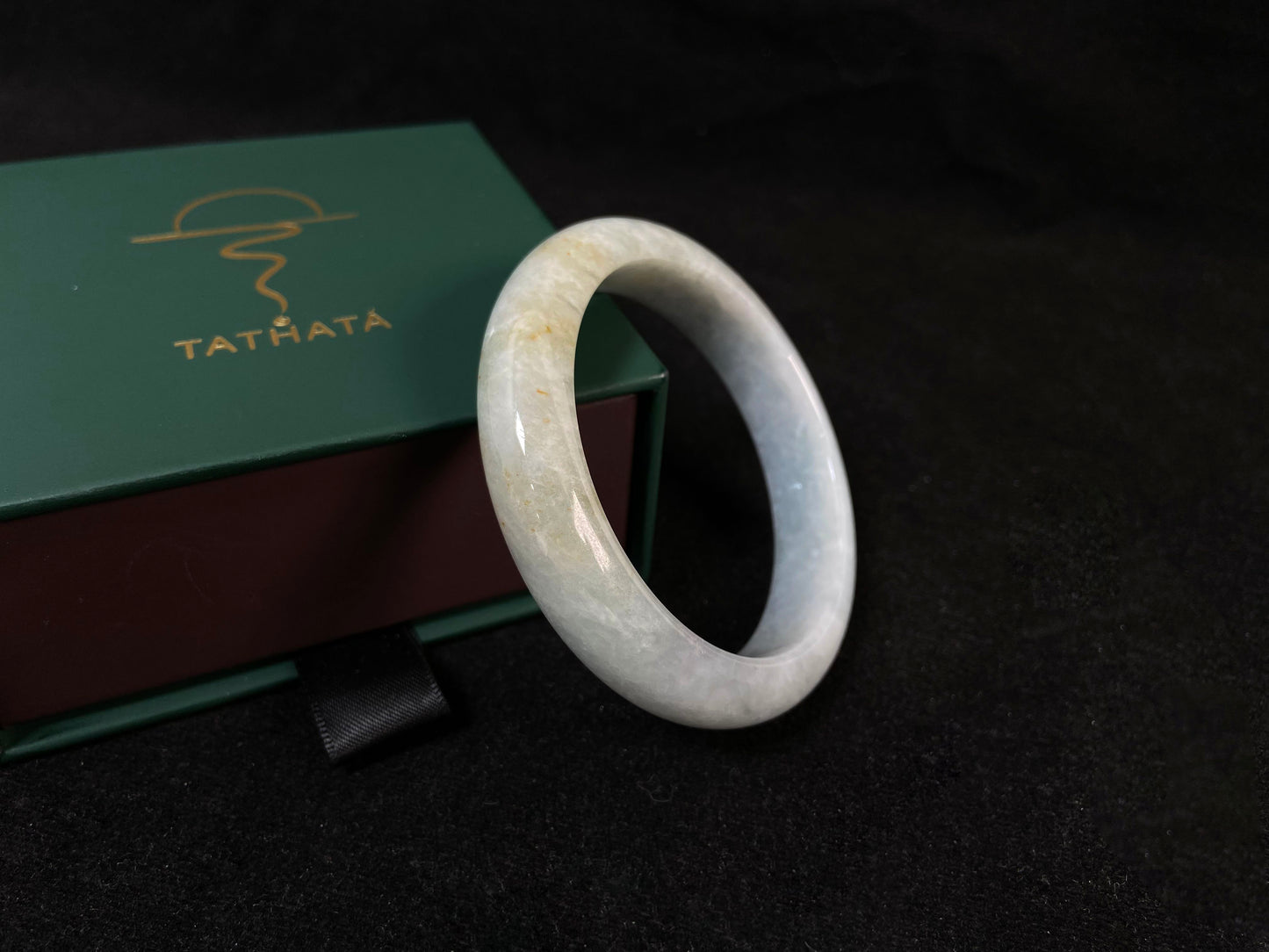 A creamy white jade bangle delicately sprinkled with gold.