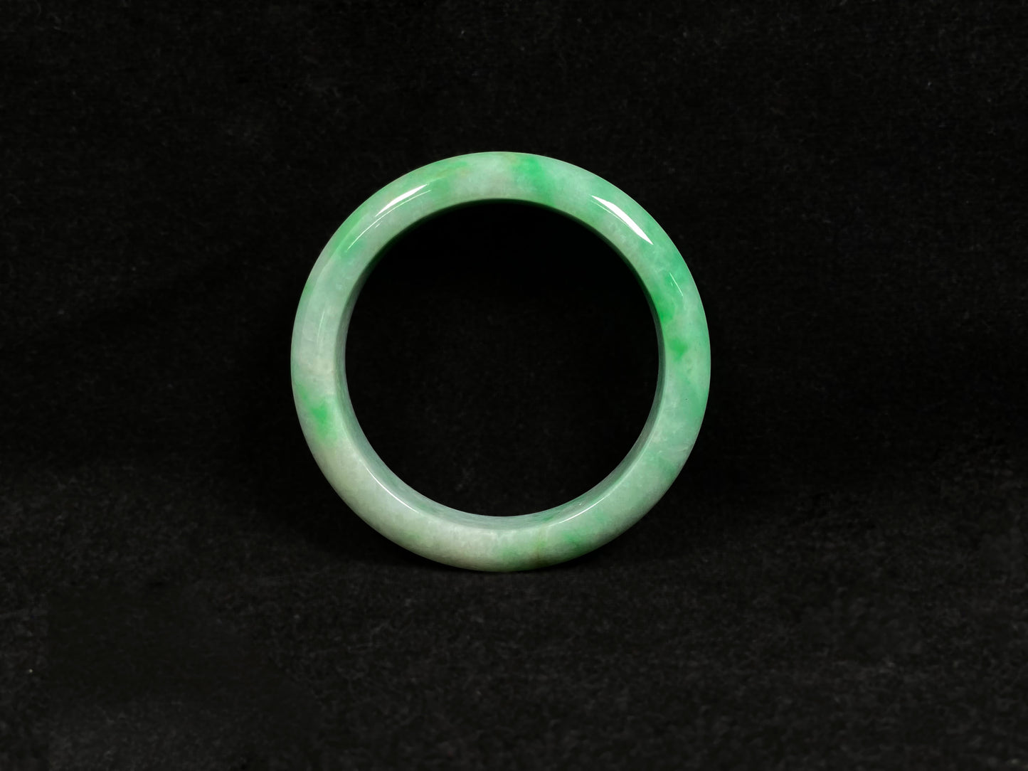 A radiant white jade bangle adorned with vibrant yang green.