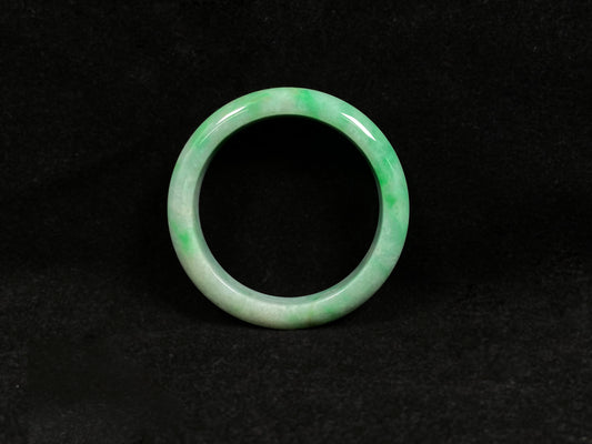A radiant white jade bangle adorned with vibrant yang green.