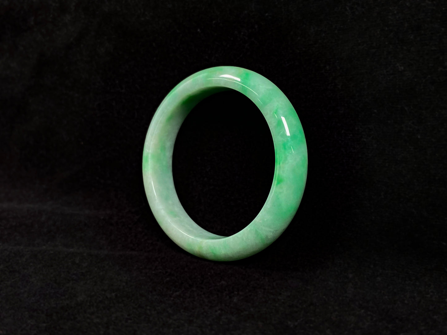 A radiant white jade bangle adorned with vibrant yang green.