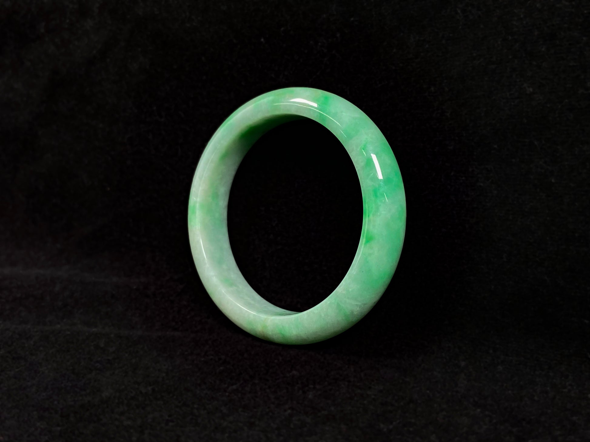 A radiant white jade bangle adorned with vibrant yang green.