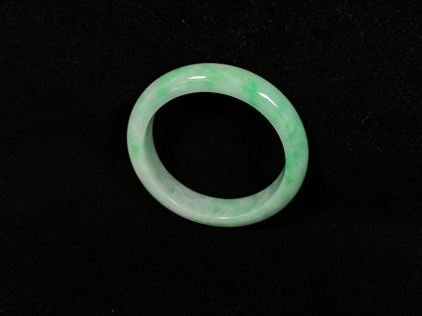 A radiant white jade bangle adorned with vibrant yang green.