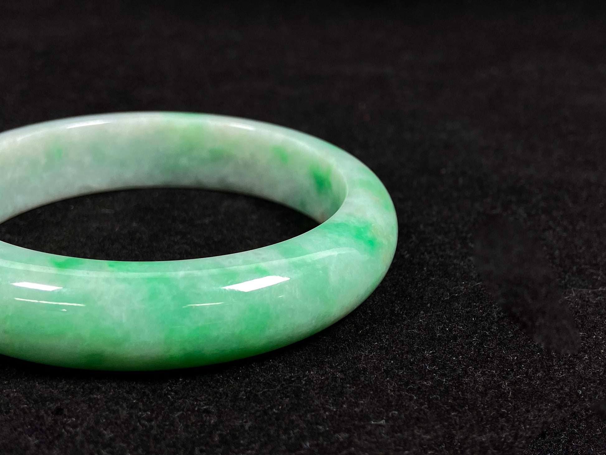 A radiant white jade bangle adorned with vibrant yang green.