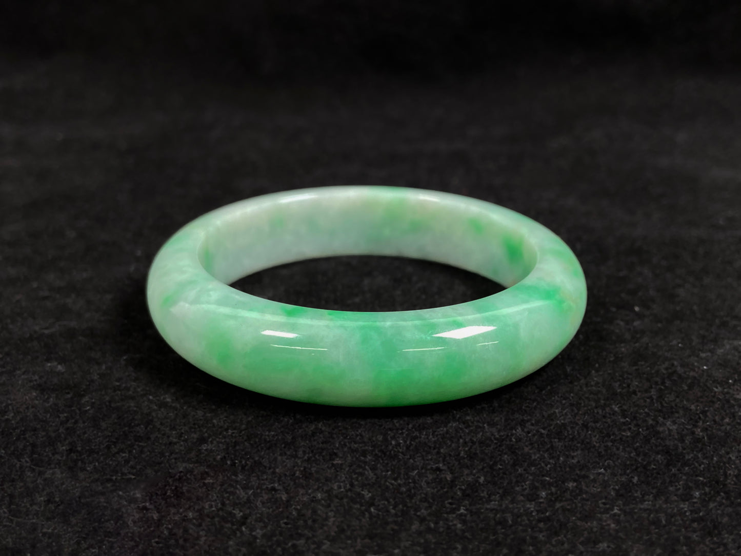 A radiant white jade bangle adorned with vibrant yang green.