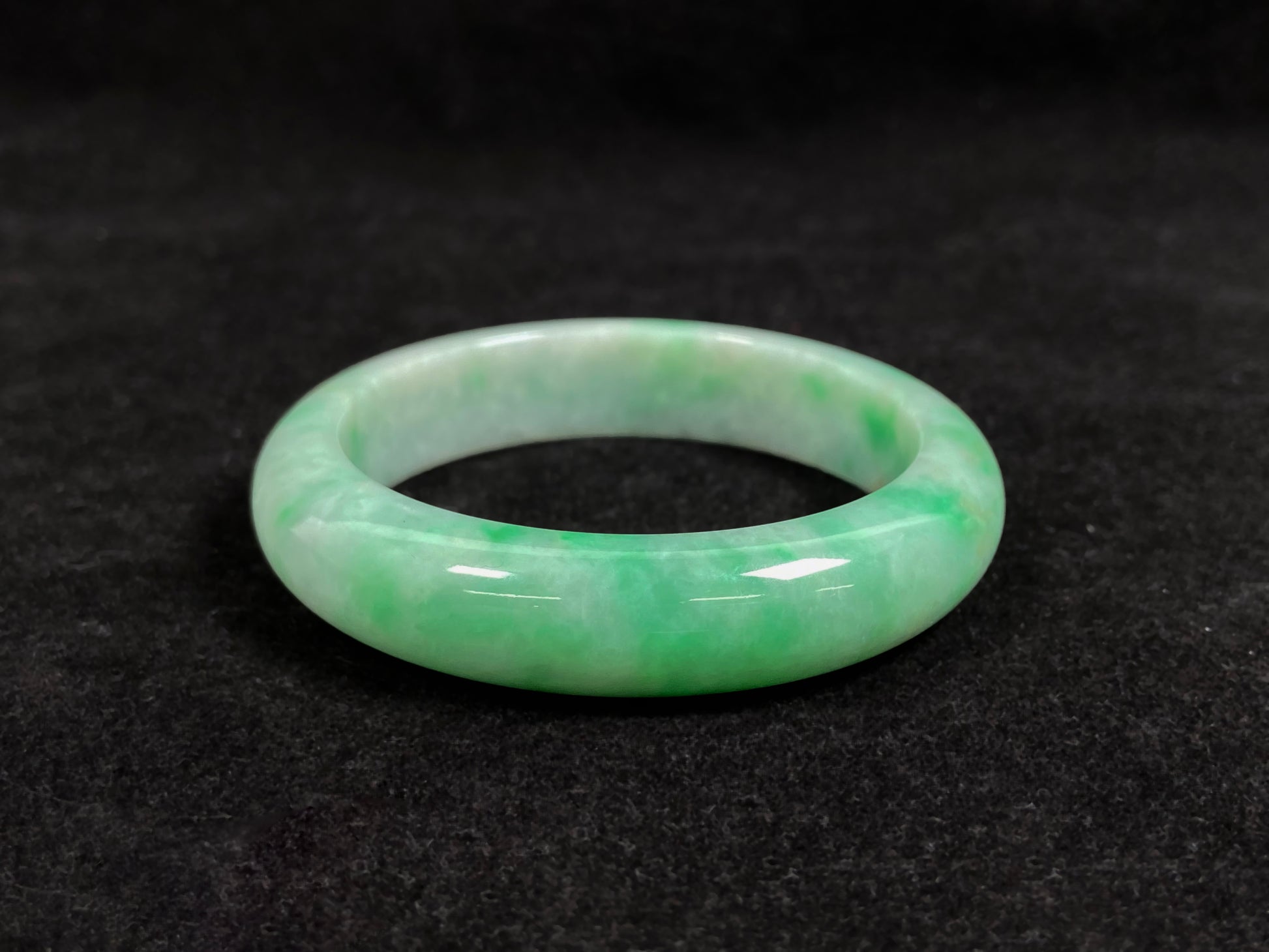 A radiant white jade bangle adorned with vibrant yang green.