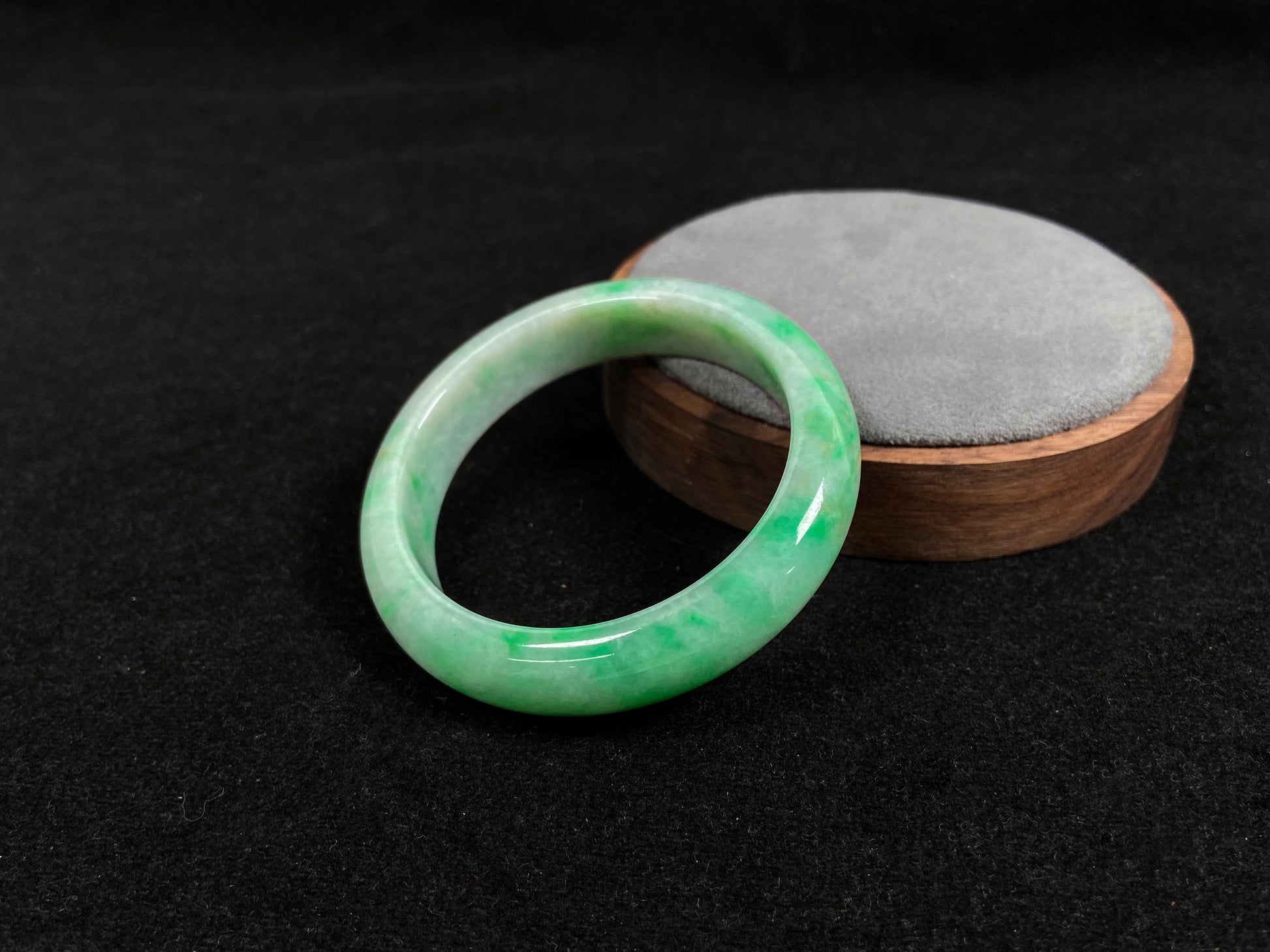 A radiant white jade bangle adorned with vibrant yang green.