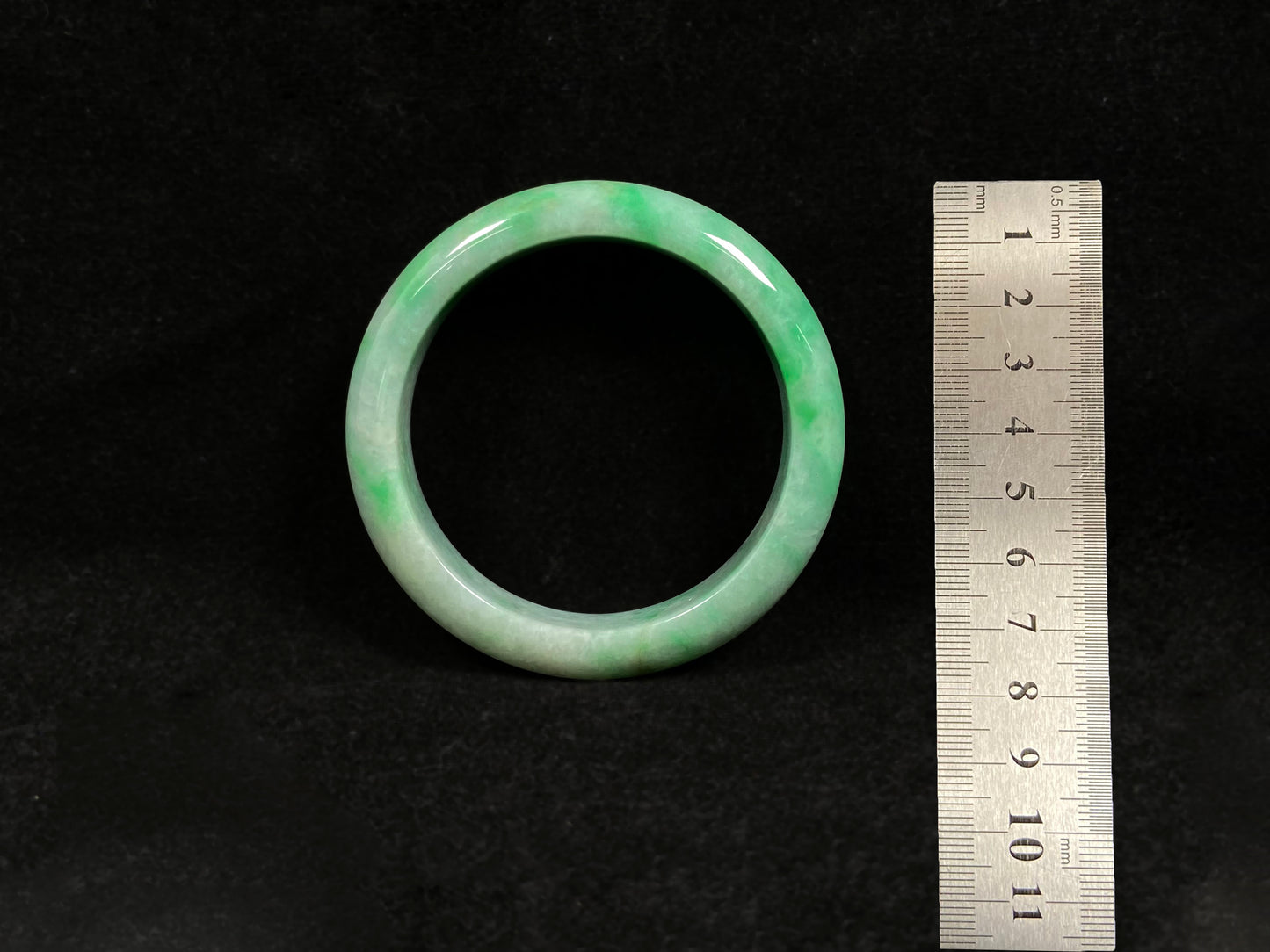A radiant white jade bangle adorned with vibrant yang green.