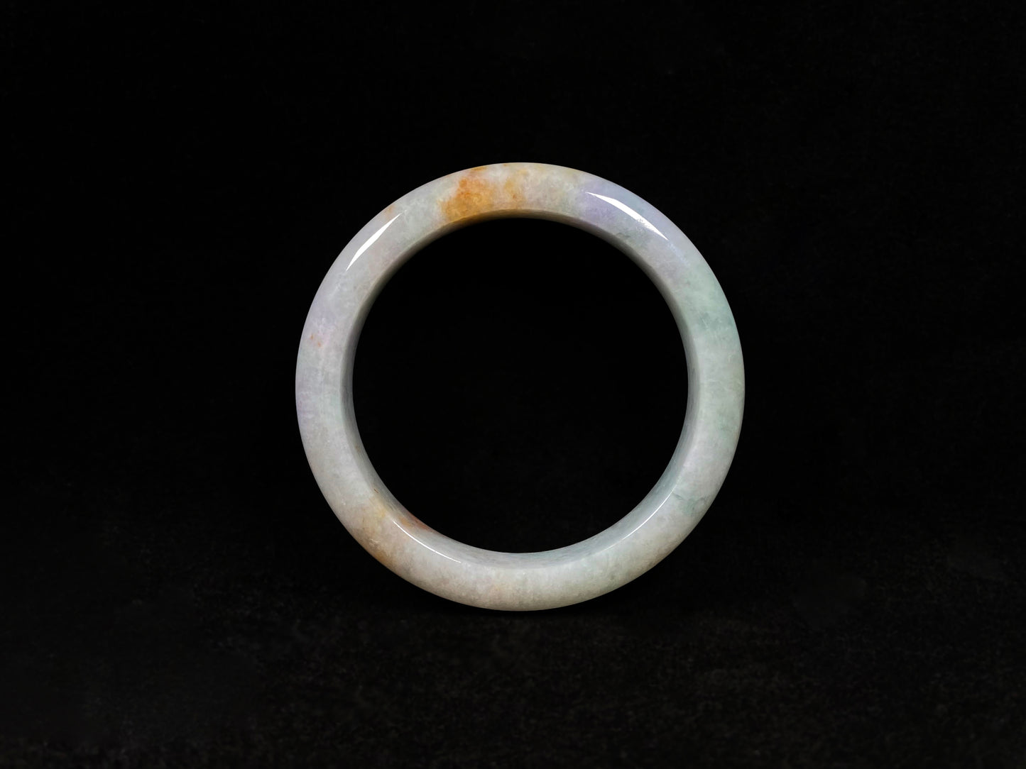 This tricolor jadeite bangle combines yellow, purple, and green, symbolizing fortune, prosperity, and longevity.
