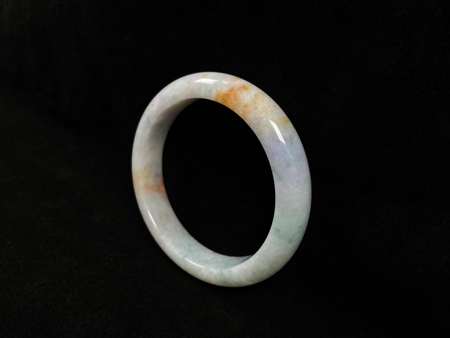 This tricolor jadeite bangle combines yellow, purple, and green, symbolizing fortune, prosperity, and longevity.