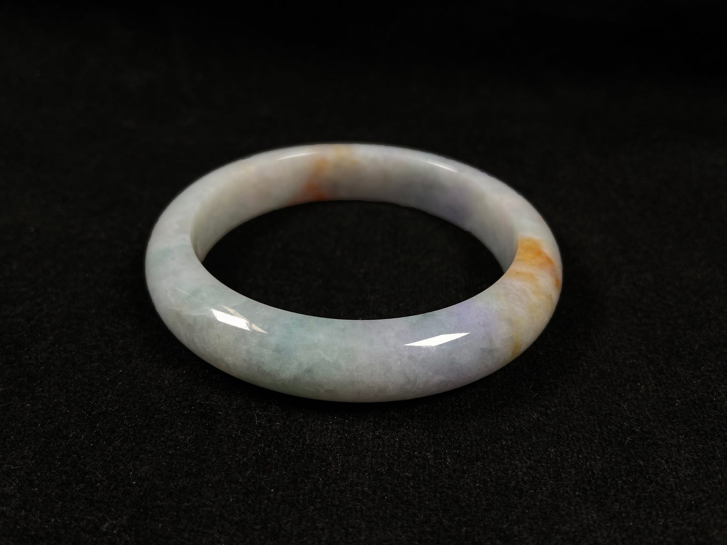 This tricolor jadeite bangle combines yellow, purple, and green, symbolizing fortune, prosperity, and longevity.