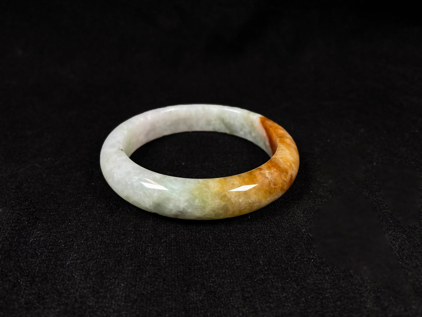 This elegant jadeite bangle features a harmonious blend of yellow, white, and light green tones.