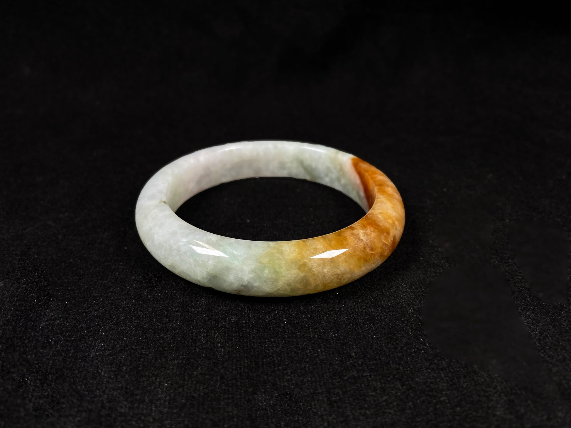 This elegant jadeite bangle features a harmonious blend of yellow, white, and light green tones.