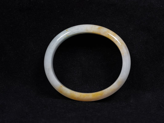 This jadeite bangle features a pale white base with soft green and warm yellow hues blending gently.