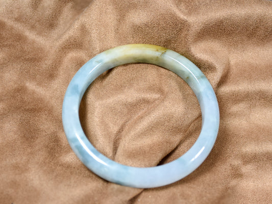 Translucent blue-green jade bracelet on a brown fabric background