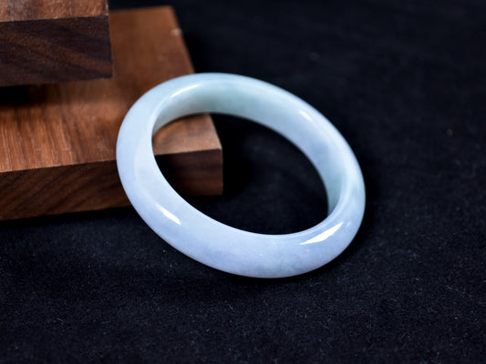 Jade bracelet on a dark surface with wooden background