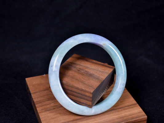Jade bracelet on a wooden stand with a dark background