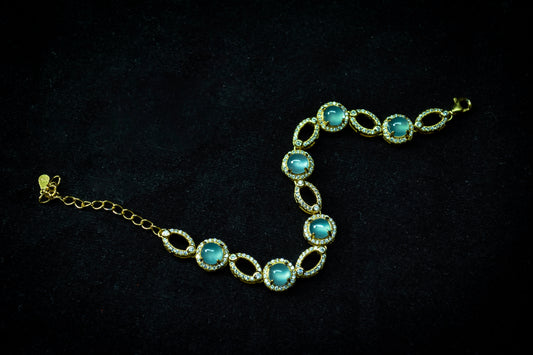 Gold bracelet with blue gemstones on a black background