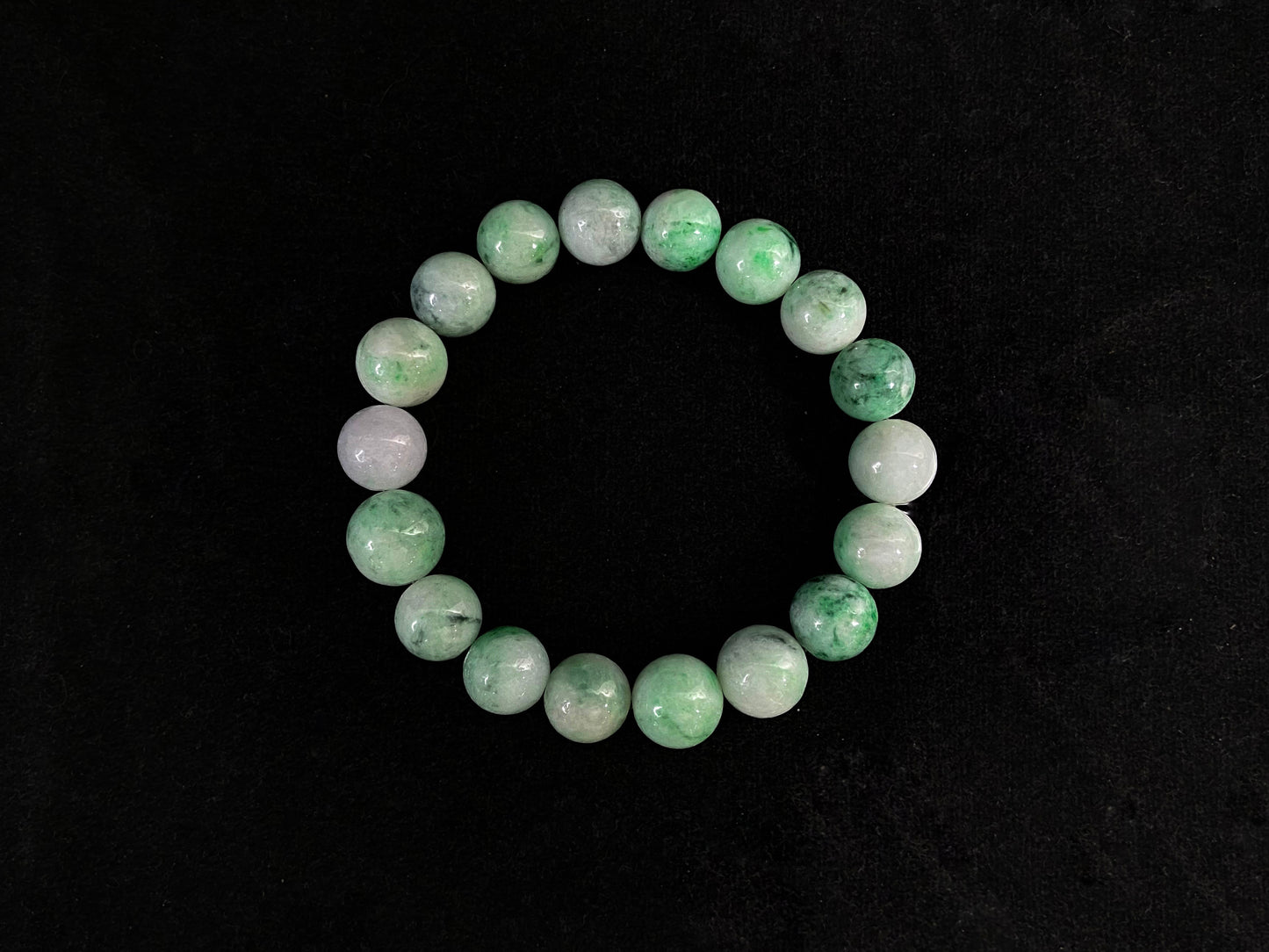 This jadeite bead strand has white based beads accented with green, plus one pale purple bead for pairing.