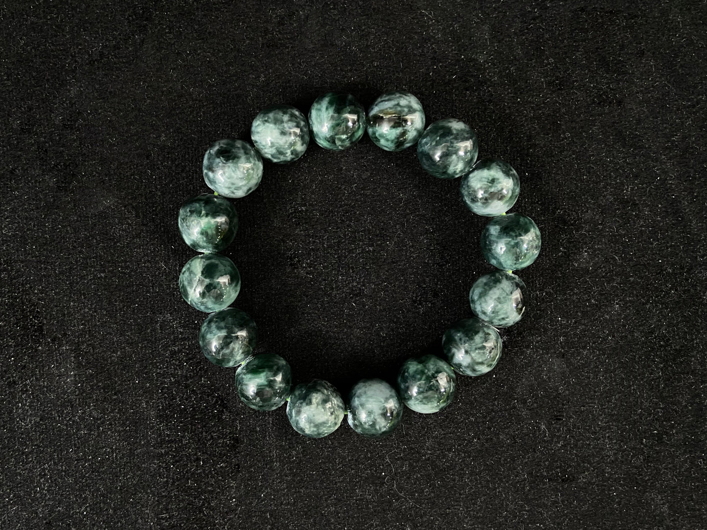 This jadeite bead strand has uniformly sized beads in mixed black, white and green.
