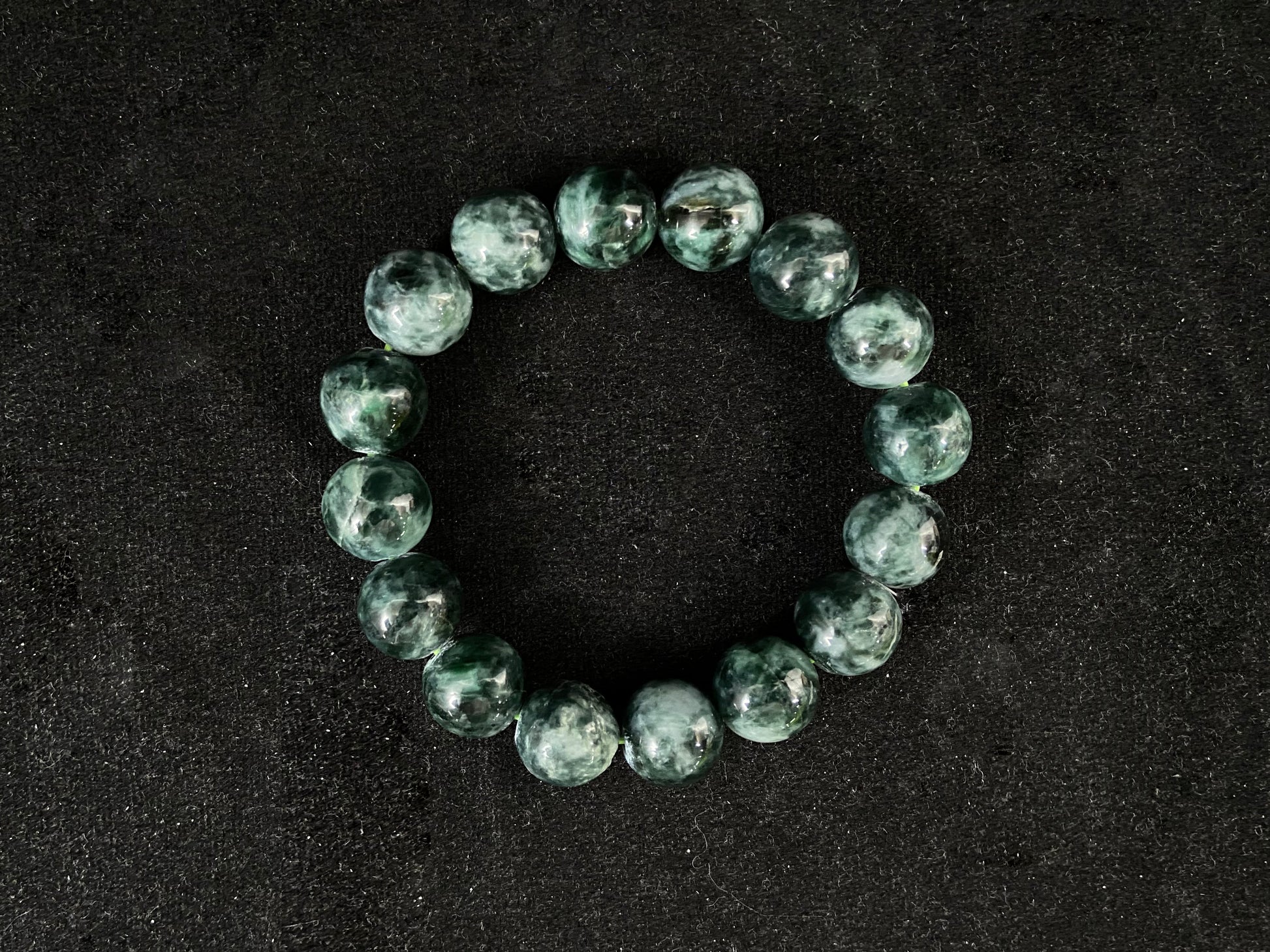 This jadeite bead strand has uniformly sized beads in mixed black, white and green.