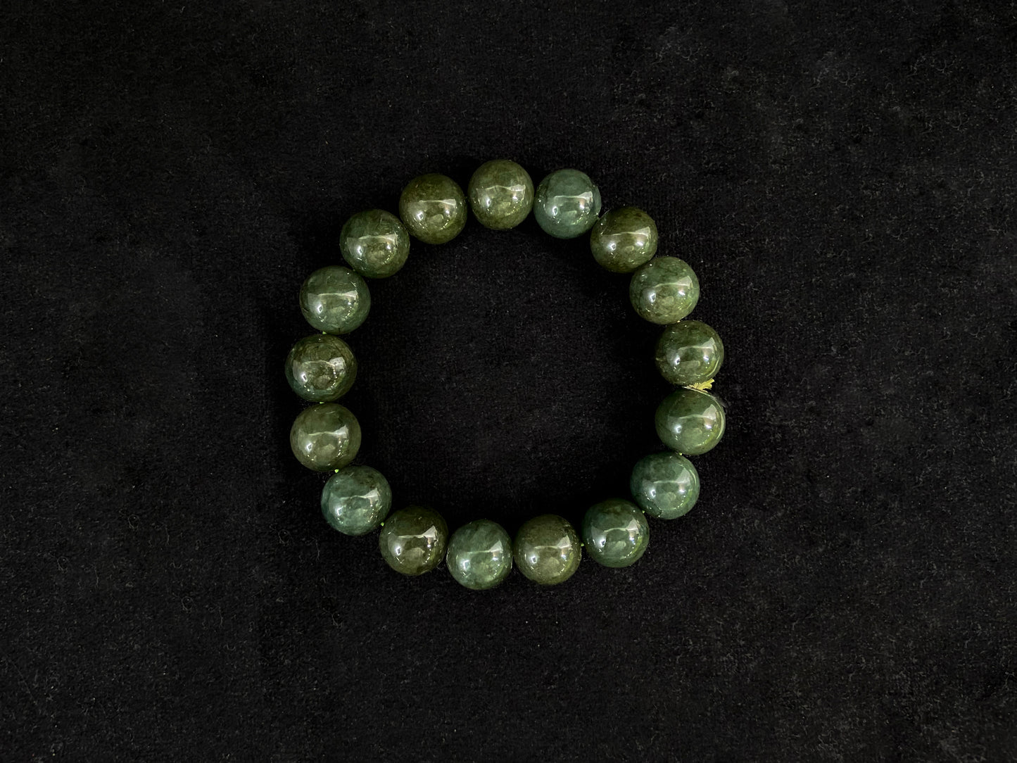 This jadeite bead strand has uniformly sized dark green beads accented with gold.