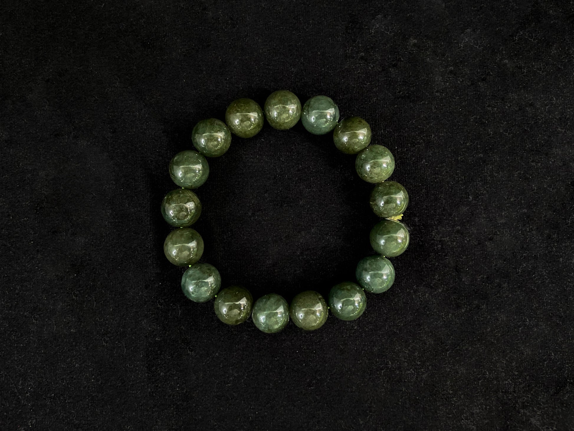 This jadeite bead strand has uniformly sized dark green beads accented with gold.