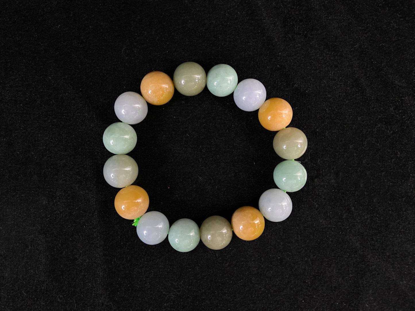 This jadeite bead strand is composed of beads in shades of pale purple, yellow, pale green and pale brown.
