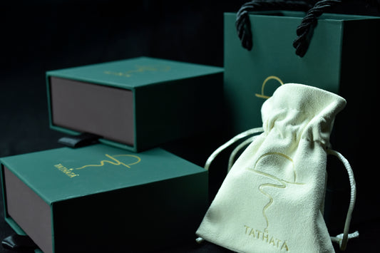Green jewelry box and white drawstring pouch with 'Tathagat' branding on a dark background
