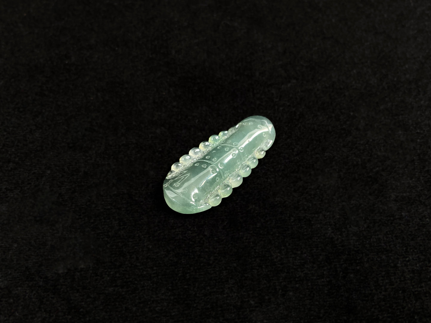 A pale green jadeite loose stone carved in the shape of a bamboo stalk.