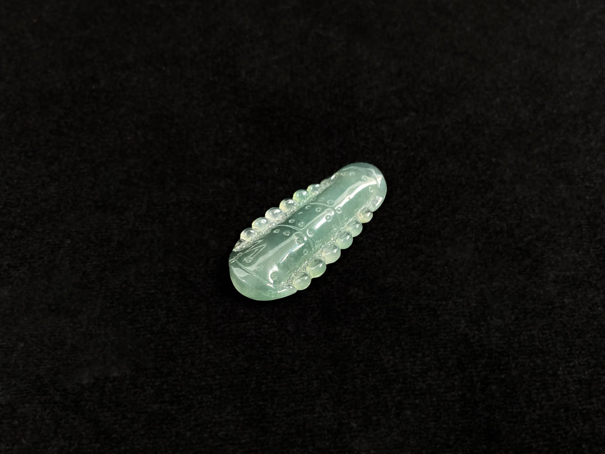 A pale green jadeite loose stone carved in the shape of a bamboo stalk.