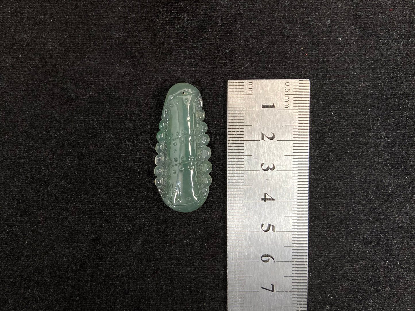 A pale green jadeite loose stone carved in the shape of a bamboo stalk.