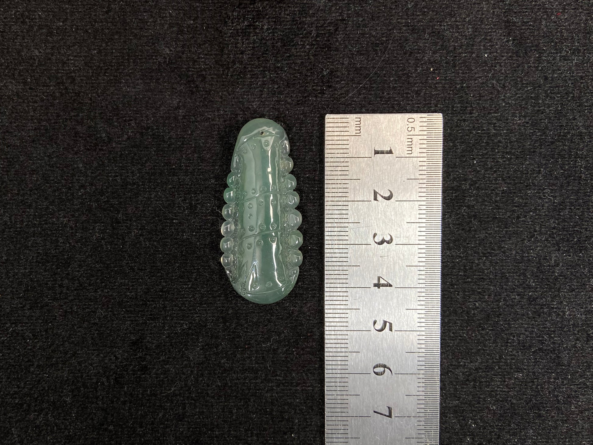 A pale green jadeite loose stone carved in the shape of a bamboo stalk.