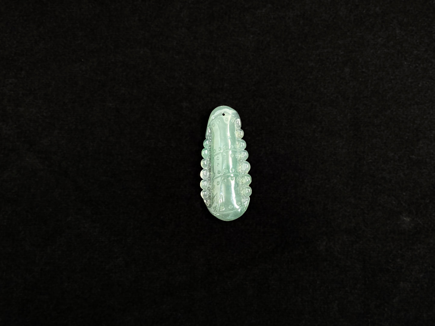 A pale green jadeite losse stone carved in the shape of a bamboo stalk.