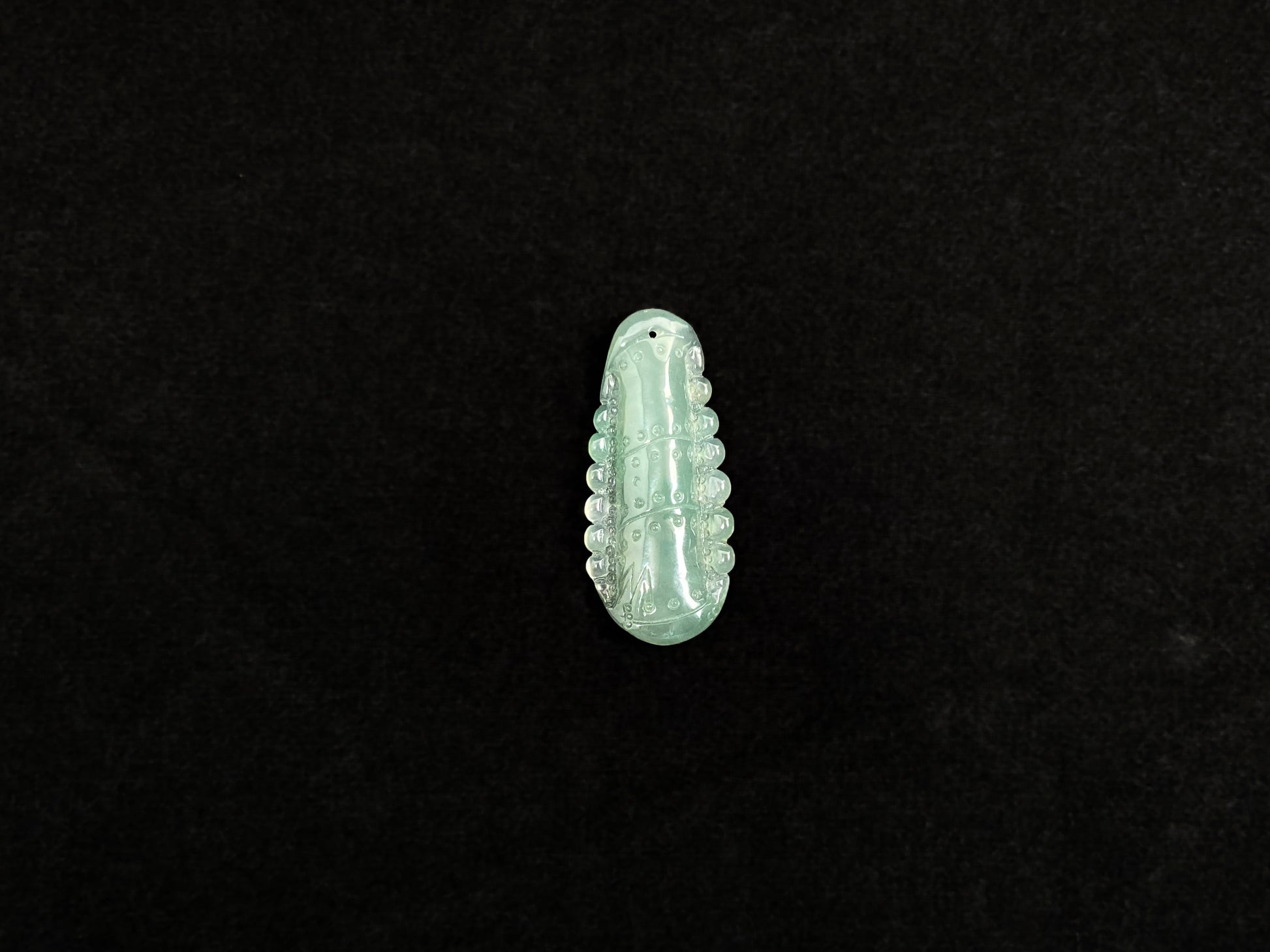 A pale green jadeite losse stone carved in the shape of a bamboo stalk.