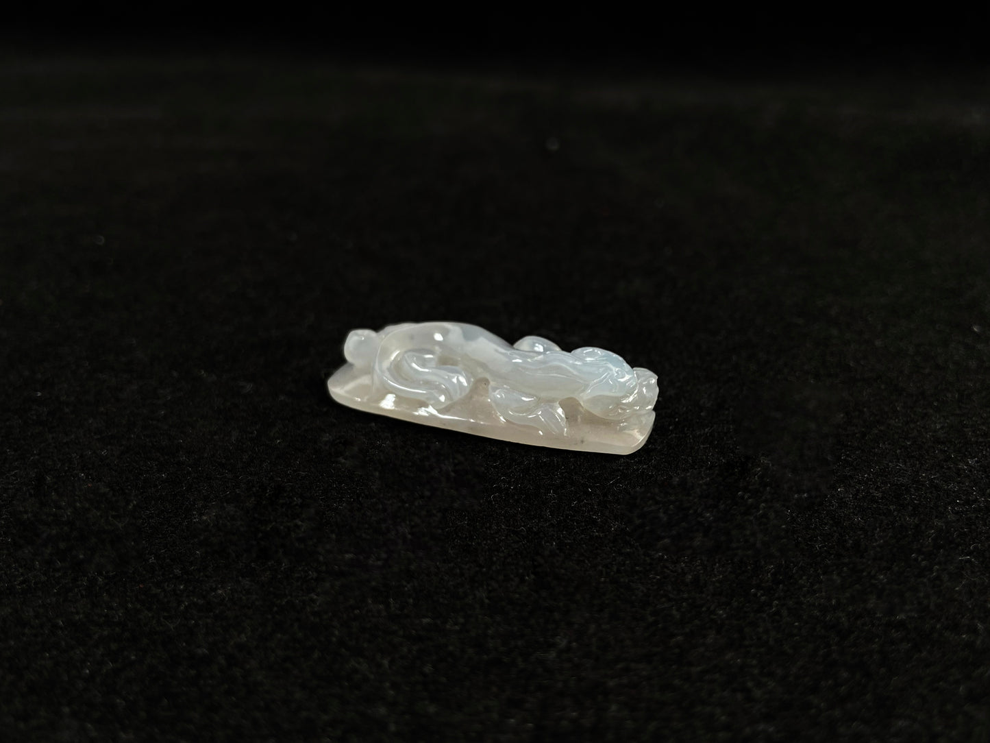This jadeite is carved into a dragon motif in semi-transparent, milky white jade.