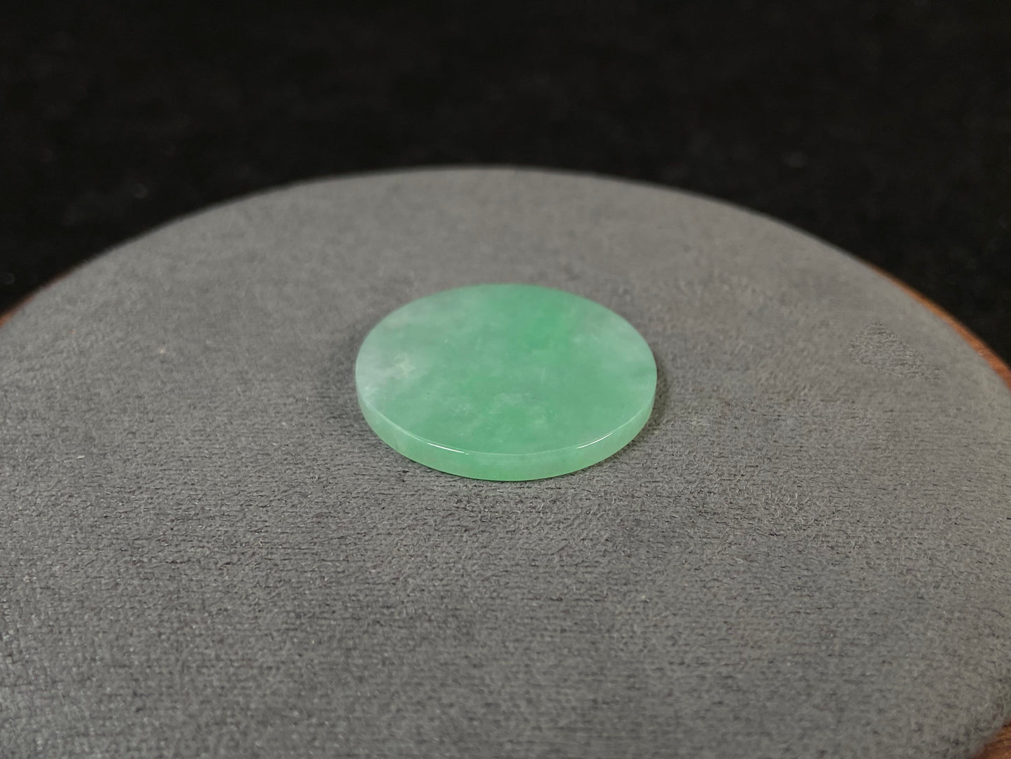 A delicate green jade stone with circular proportions.