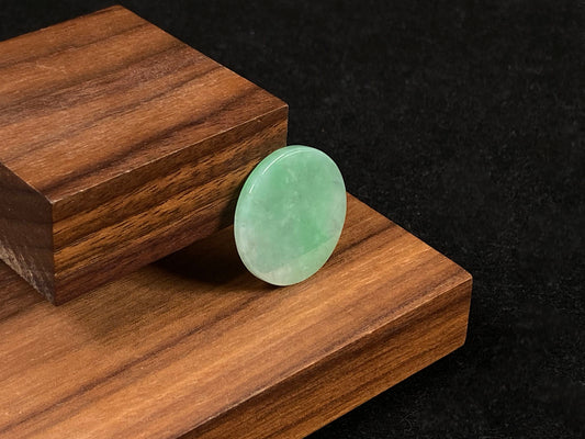 A delicate green jade stone with circular proportions.