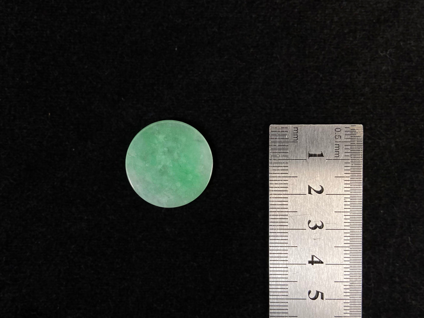 A delicate green jade stone with circular proportions.