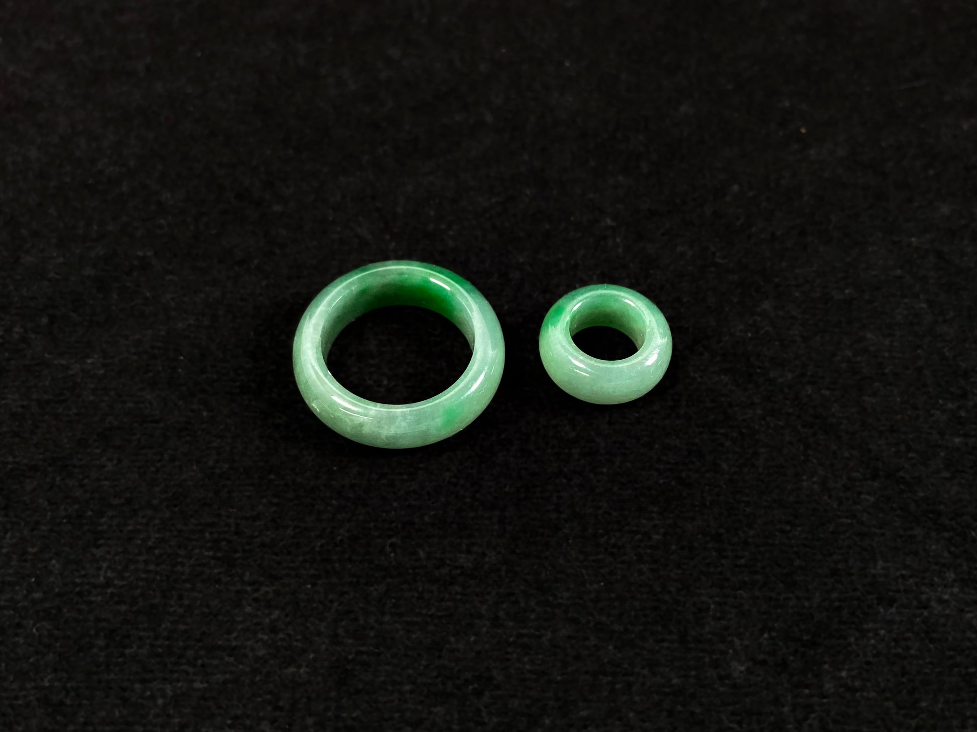 A loose jadeite with a light green base and vibrant green mother-child pendant accents.