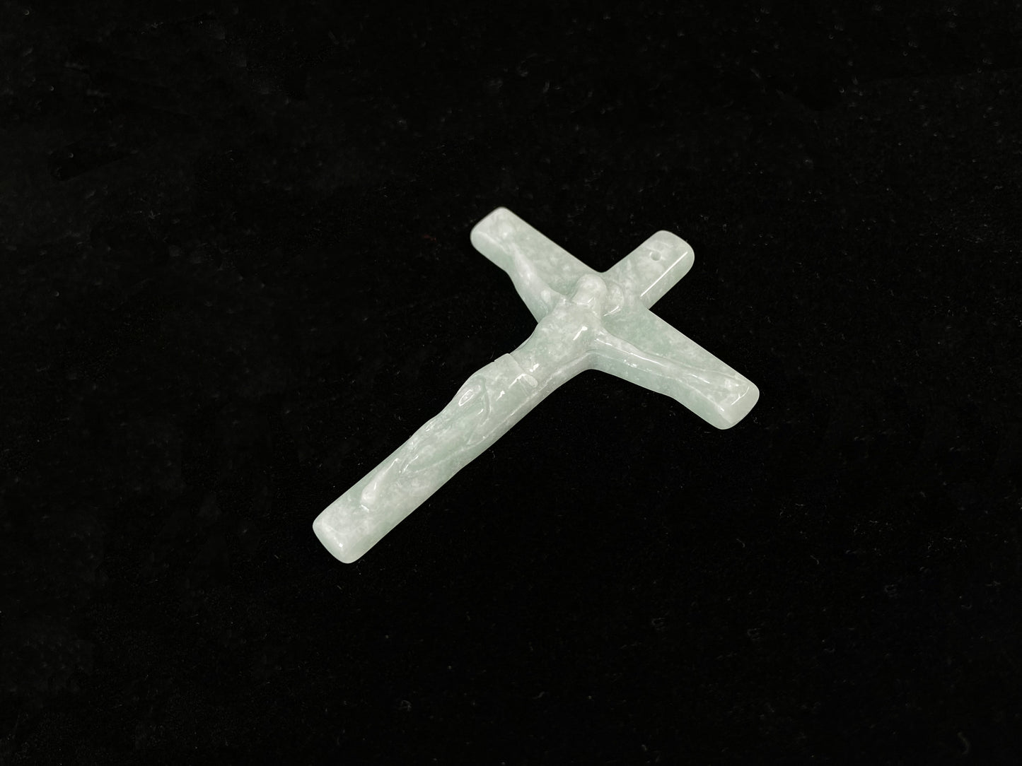 A bean green jadeite cross pendant featuring Jesus.