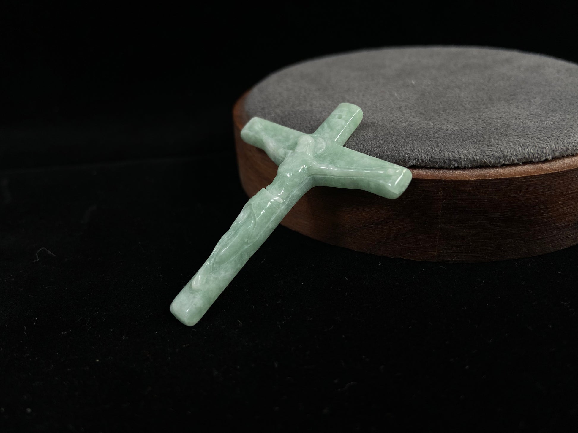 A bean green jadeite cross pendant featuring Jesus.