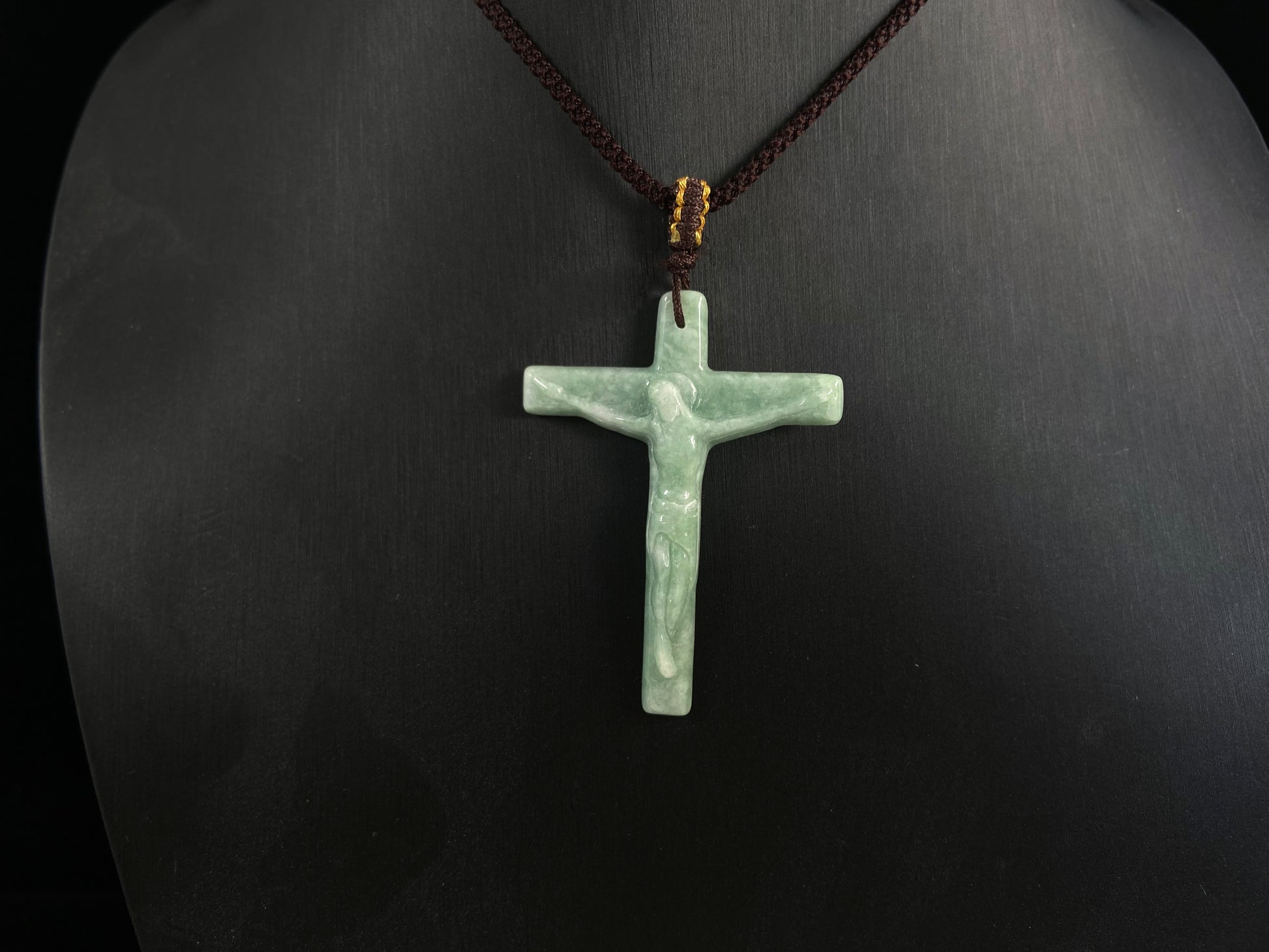 A bean green jadeite cross pendant featuring Jesus.