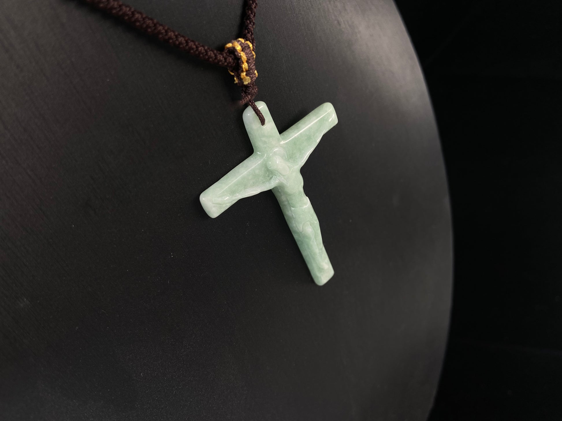 A bean green jadeite cross pendant featuring Jesus.